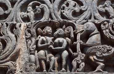 Example of Indian architecture background on traditional style relief, with friendship of fantasy animals and ancient people. Carvings on front of 12th century Hoysaleshwara temple in Halebidu, India.