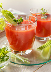 Two glasses of fresh tomato juice with thyme and celery.