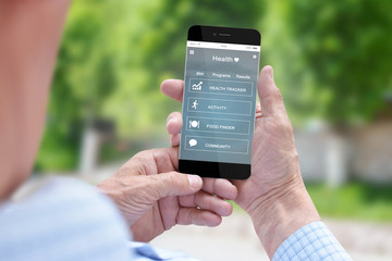 Old man holding smartphone with health app. User interface flat design. Blurred outdoor background
