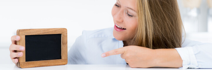 Blonde junge Frau zeigt auf Hinweisschild