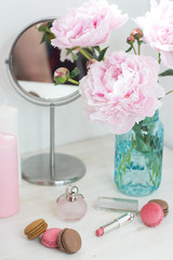 Bouquet of pink peonies in a vase. Bouquet of peonies in a vase, macaroon, cosmetics on the table. Dressing table.