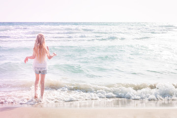 Fototapeta premium Young blonde girl standing on the beach