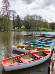 Multicolored boats and pedal boats on a pond waiting to be hired.