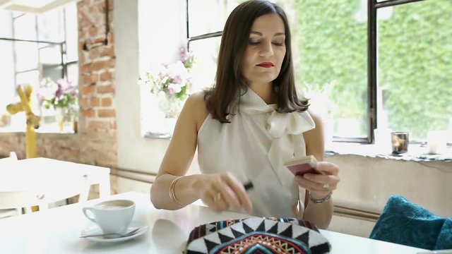 Elegant woman taking lipstick from her bag and applying on the lips, steadycam shot

