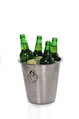 Close-up view of ice cubes, lemon slices and green beer bottles in bucket isolated on white