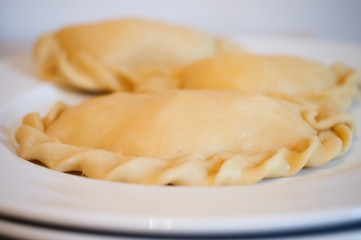 Raw empanadas on white plate ready to get baked