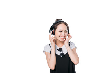 smiling asian girl listening music in headphones isolated on white