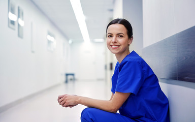 smiling female nurse at hospital corridor - obrazy, fototapety, plakaty
