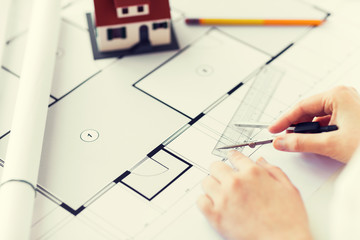 close up of hands with compass measuring blueprint