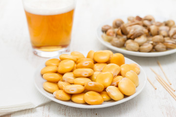 salted lupins on white plate and snails with glass of beer