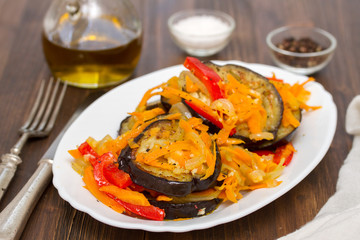 fried eggplant with garlic, carrot and red pepper on white dish