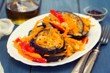 fried eggplant with garlic, carrot and red pepper on white dish