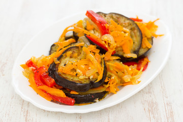 fried eggplant with garlic, carrot and red pepper on white dish