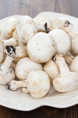 fresh mushrooms in white plate on wooden background
