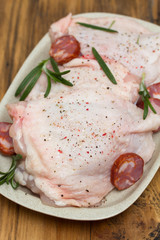 raw chicken with smoked sausage and rosemary on white dish