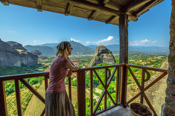 Woman tourist looking panorama from famous Monastery of Holy Trinity in Meteora, Peloponnese, Thessaly, Greece. Tourism and travel in European scenic destinations. Agia Triada is Unesco Heritage Site.