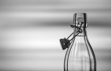 Fototapeta na wymiar Open glass bottle in front of a creative black and white background