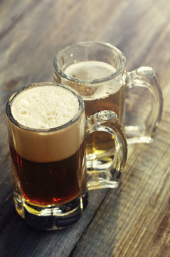 Two glasses of beer on a wooden board. Light and dark beer in glasses