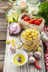 Jug of olive oil, pasta, tomatoes, herbs, salt, pepper, ingredients for cooking on a simple wooden kitchen table. selective focus