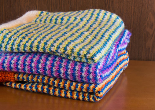 Stack of warm clothes on wooden table. Selective focus