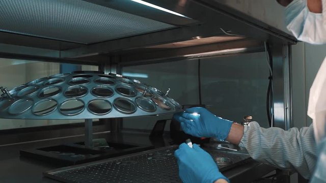 Caucasian man scientist in white robe blue rubber gloves cleaning lens with cotton swab at laboratory working place