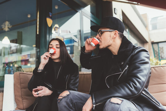 Young couple sitting outdoor in a bar having a coffee - relaxing, break concept