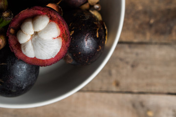 Top view of mangosteen fruit in the bowl over wooden table background