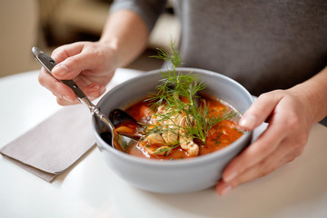 woman eating seafood soup at restaurant
