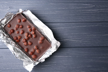 Chocolate bar with nuts in foil on table