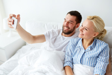 happy couple with smartphone taking selfie at home