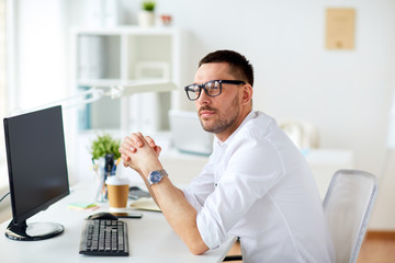 businessman in glasses sitting at office computer