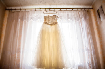 beautiful wedding dress hanging in the bride's room.