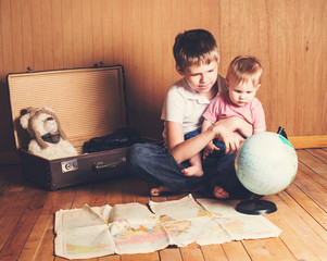 Adventure. Boy with his baby sister preparing for the journey. Brother holding his little sister study the map and choose a route of travel.