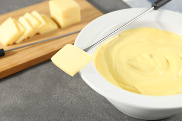 Slice of cheese and fondue on table, closeup
