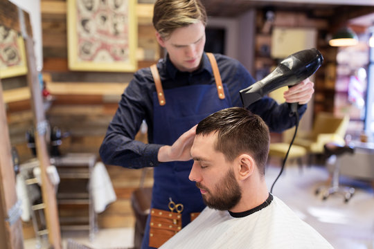 barber with fan drying male hair at barbershop