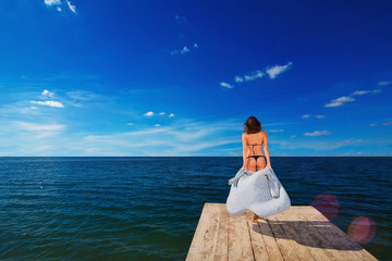 young beautiful woman going to ocean on wooden pier