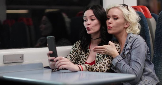 Young adult female friends travelling on a night train taking selfie