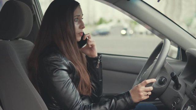 Young woman is emotionally quarreling by phone in the car