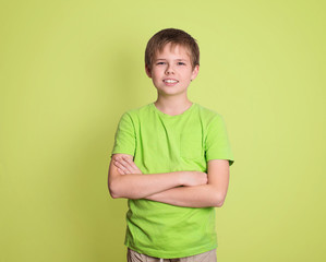 Confident preteen boy portrait with arms crossed isolated on green background. © Polina Ponomareva