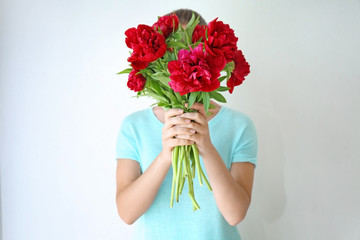 Young woman holding bunch of peonies on white background