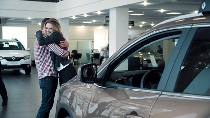 Man Standing Behind Woman and Covering Her Eyes While Standing in front of Shiny New Red Vehicle...