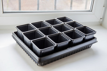 New empty plastic containers for vegetable seedlings on the windowsill