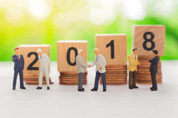 wooden block number 2018 with stack coins behide business men using as background new year or business concept.