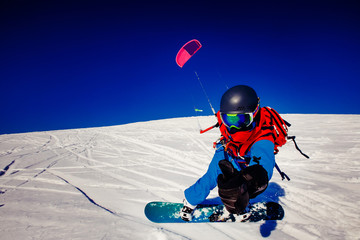 Fototapeta na wymiar Snowboarder with a kite on fresh snow in the winter in the tundra of Russia against a clear blue sky. Teriberka, Kola Peninsula, Russia. Concept of winter sports snowkite.