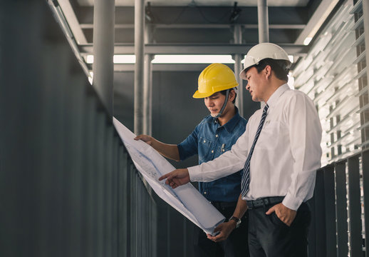 Engineers In Mechanical Factory Reading Instructions.Engineer And Businessman Meeting, Team Discussion With Construction On Site Work.