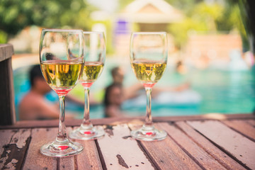 Elegant flute glass of sparkling white wine or champagne at swimming pool on holidays.