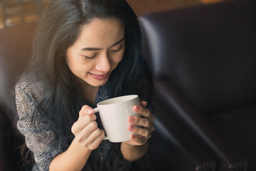Woman's hands in sweater holding cup of coffee