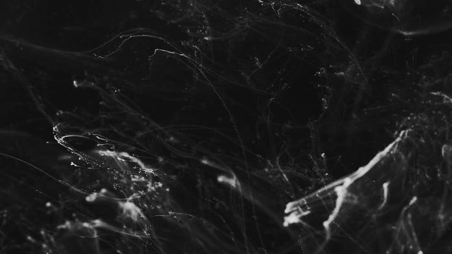 White particles and ink slowly moving on black background,