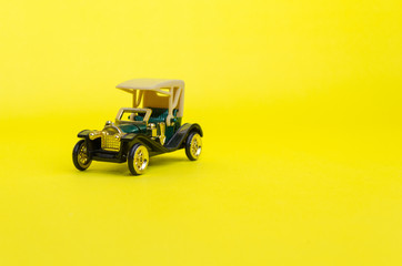 ancient green convertible classic car, old toy car on yellow background, selective focus, copy space