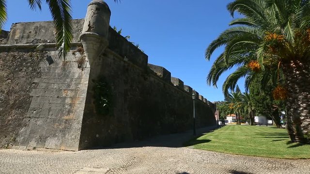 Old high fortifying wall in city with sidewalk along it, panorama and sequence